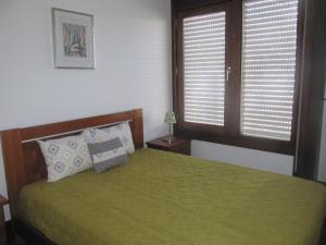 1 Schlafzimmer mit einem grünen Bett und 2 Fenstern in der Unterkunft Troia Mare Nostrum in Troia