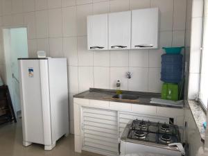 a kitchen with a white refrigerator and a stove at Kitnet Central II in Arraial do Cabo