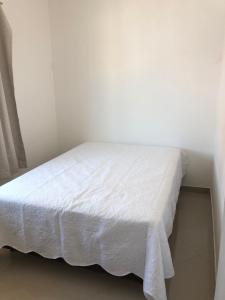 a bed in a room with a white bedspread at Kitnet Central II in Arraial do Cabo