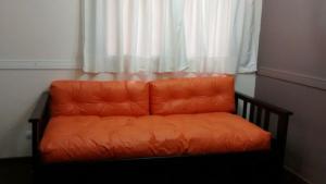 un sofá naranja sentado frente a una ventana en Departamentos Mendoza en Mendoza