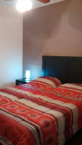 1 dormitorio con 1 cama con manta roja y blanca en Departamentos Mendoza en Mendoza