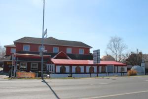 a red building with a red roof next to a street at Motelnet.T in Mosonmagyaróvár