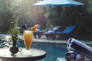 a drink sitting on a table next to a pool at Sri Phala Resort & Villa in Sanur