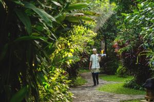 a man walking down a path in the jungle at Sri Phala Resort & Villa in Sanur