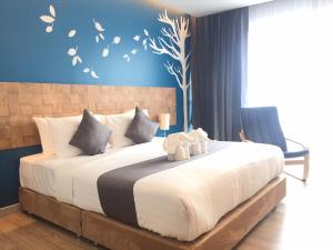 een slaapkamer met een groot bed met een teddybeer erop bij Slive Hotel in Surin