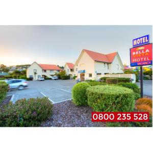 a hotel sign and a parking lot with a motel at Bella Vista Motel Oamaru in Oamaru