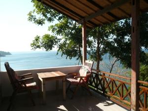 two chairs and a table on a porch with the ocean at Wawa Wewe Rock in Amed