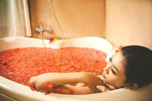 a woman laying in a bath tub filled with red peppers at Sri Phala Resort & Villa in Sanur