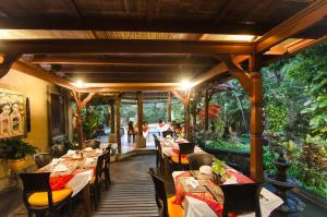 a dining room with tables and chairs and trees at Sri Phala Resort & Villa in Sanur
