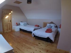 a bedroom with two beds and a wooden floor at Barnagowlane House in Barnagowlane