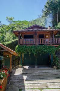 een houten huis met een balkon erboven bij Chalés Lirio dos Vales in Visconde De Maua