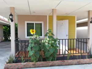 ein gelbes Haus mit Sonnenblume auf der Veranda in der Unterkunft Deva Garden Resort in Prachin Buri