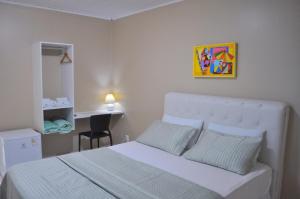 a bedroom with a white bed and a desk at Goyanna Hotel in Goiana