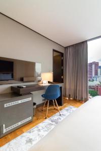 a bedroom with a desk and a blue chair at Ramada Encore by Wyndham Makati in Manila