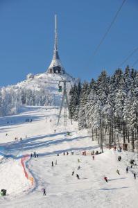 a group of people skiing down a ski slope with a ski lift at Hotel Ještěd in Liberec