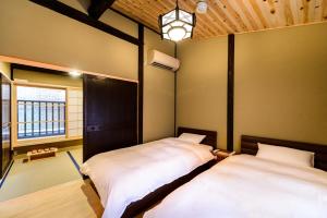 a bedroom with two beds and a window at Nadeshiko Shirakawa Machiya House in Kyoto