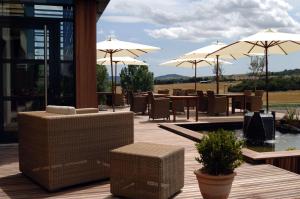 een patio met tafels, stoelen en parasols bij Best Western Plus Hôtel Gergovie in Pérignat-lès-Sarliève