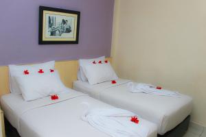 two beds in a room with red bows on them at Sabrina Paninsula in Pekanbaru