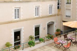 a balcony with chairs and tables and an umbrella at Best Western Poitiers Centre Le Grand Hôtel in Poitiers