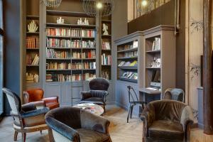 uma biblioteca com cadeiras e estantes de livros com livros em Best Western Citadelle em Besançon