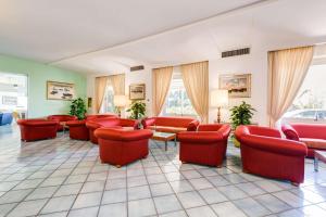 a waiting room with red chairs and tables and windows at Best Western Hotel La Solara in Sorrento