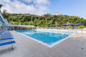 a large swimming pool with blue chairs and umbrellas at Best Western Hotel La Solara in Sorrento