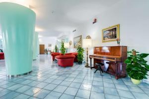 a lobby with a piano and red chairs at Best Western Hotel La Solara in Sorrento