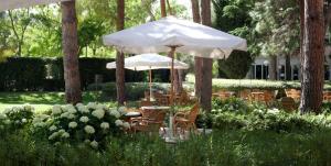 a table and chairs under an umbrella in a garden at Villa Maria Hotel & SPA in Francavilla al Mare