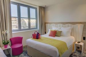 a hotel room with a bed and a pink chair at Best Western Plus Comedie Saint Roch in Montpellier +107 photos