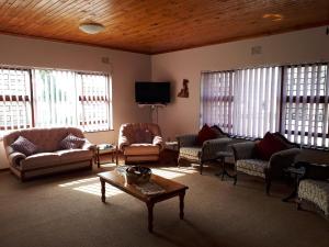 een woonkamer met banken, een tafel en ramen bij Die C Skulp in Hartenbos