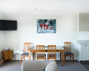 una sala da pranzo con tavolo, sedie e TV di Alpine Motel a Oamaru