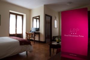 une chambre d'hôtel avec un lit et un panneau rose dans l'établissement Hotel Residenza Petra, à Petralia Soprana