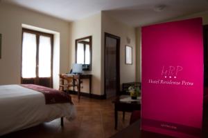a hotel room with a bed and a pink sign at Hotel Residenza Petra in Petralia Soprana