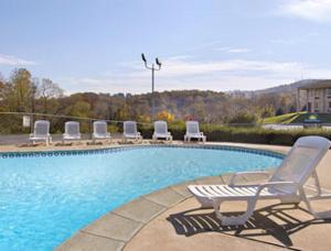 - une piscine avec des chaises longues à côté dans l'établissement Express Inn Harrisburg South New Cumberland, à New Cumberland