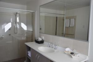 Baño blanco con lavabo y espejo en Sunray Motor Inn, en Toowoomba