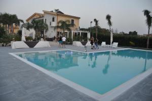 - une piscine d'eau bleue en face d'un bâtiment dans l'établissement Casa Elena, à Trapani