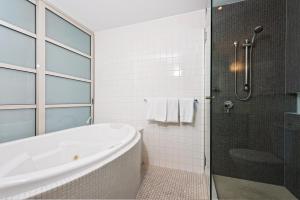 a white bathroom with a tub and a shower at Embassy Apartment North Terrace in Adelaide