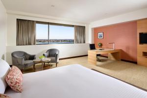 a hotel room with a bed, chair, desk and a television at Pan Pacific Perth in Perth