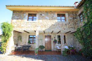 a stone house with a table and chairs in front of it at La Llosa in Villaviciosa +11 photos