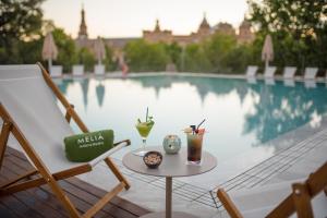 una mesa y sillas junto a una piscina en Melia Sevilla en Sevilla