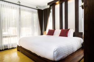 a bedroom with a large white bed with red pillows at Shinnabhura Historic Boutique Hotel in Phitsanulok
