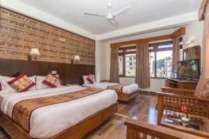a hotel room with two beds and a television at Hotel Tulsi in Pokhara