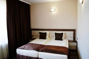 a hotel room with a bed with white sheets and pillows at Family Hotel Neliya in Velingrad