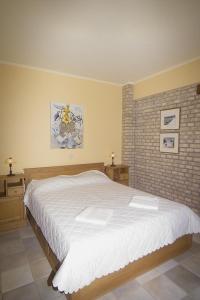 una camera da letto con un grande letto bianco e un muro di mattoni di Miltiadis Farm a Città di Lefkada