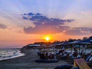 法納里翁的住宿－Villa Elaia Mare，一群人坐在海滩上,日落时分