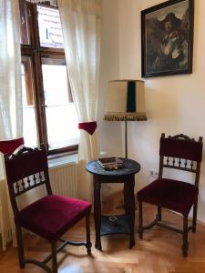 Zimmer mit einem Tisch, 2 Stühlen und einem Fenster in der Unterkunft Casa Livia Brasov in Braşov