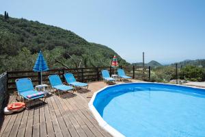 a deck with chairs and a swimming pool with a mountain at Villa Alexander in Paleokastritsa