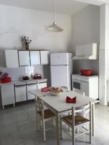 uma cozinha com mesa e cadeiras e uma cozinha branca em casa vicino mare ( sea rocks cottage) em Marina di Mancaversa