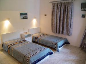 a room with two beds and a window with curtains at Villa Maro in Skopelos Town
