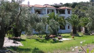 a large white house with trees in the yard at Villa Maro in Skopelos Town